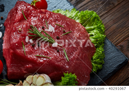 Composition of raw beefsteak on slate board with vegetables and seasoning, selective focus, close-up 40291067