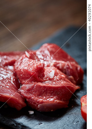 Composition of raw beefsteak on slate board with vegetables and seasoning, selective focus, close-up 40291074
