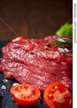 Composition of raw beefsteak on slate board with vegetables and seasoning, selective focus, close-up 40291088