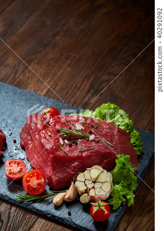Composition of raw beefsteak on slate board with vegetables and seasoning, selective focus, close-up 40291092