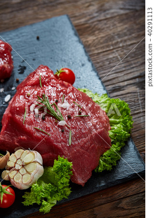 Composition of raw beefsteak on slate board with vegetables and seasoning, selective focus, close-up 40291113