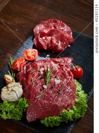 Composition of raw beefsteak on slate board with vegetables and seasoning, selective focus, close-up 40291114