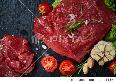 Composition of raw beefsteak on slate board with vegetables and seasoning, selective focus, close-up 40291116