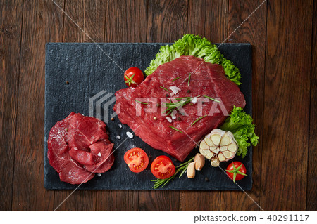 Composition of raw beefsteak on slate board with vegetables and seasoning, selective focus, close-up 40291117