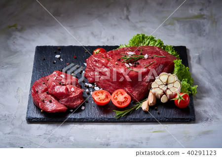 Composition of raw beefsteak on slate board with vegetables and seasoning, selective focus, close-up 40291123