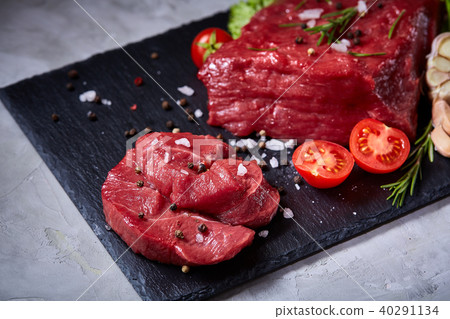 Composition of raw beefsteak on slate board with vegetables and seasoning, selective focus, close-up 40291134