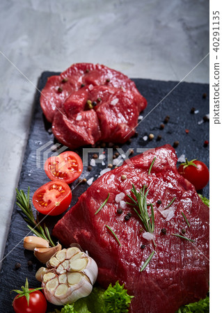 Composition of raw beefsteak on slate board with vegetables and seasoning, selective focus, close-up 40291135