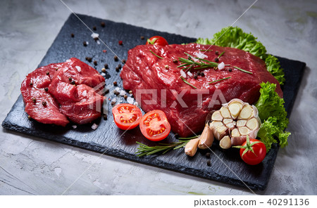 Composition of raw beefsteak on slate board with vegetables and seasoning, selective focus, close-up 40291136