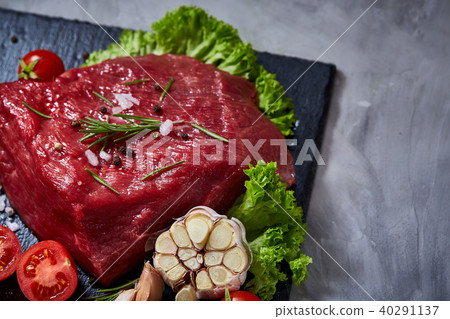 Composition of raw beefsteak on slate board with vegetables and seasoning, selective focus, close-up 40291137
