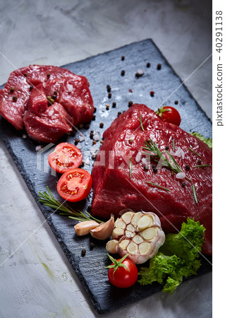 Composition of raw beefsteak on slate board with vegetables and seasoning, selective focus, close-up 40291138