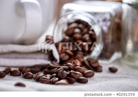 Roasted coffee beans get out of overturned glass jar on white background, selective focus, side view 40291359