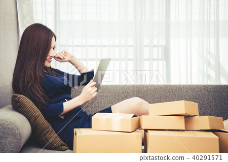 Asian woman is shopaholic on tablet full of boxes Asian woman is shopaholic on tablet full of boxes 40291571