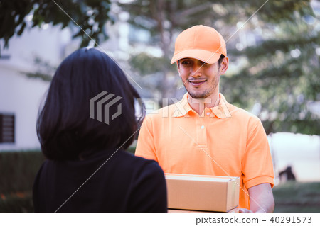 Delivery man in orange handing packages to a woman Delivery man in orange handing packages to a woman 40291573