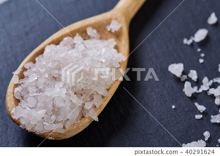 Crystal sea salt in a wooden spoon on dark background, top view, close-up, selective focus. 40291624