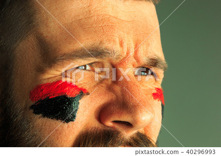 Portrait of a man with the flag of the Germany painted on him face. Portrait of a man with the flag of the Germany painted on him face. 40296993