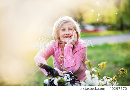 Beautiful senior woman with bicycle outside in spring nature. Beautiful senior woman with bicycle outside in spring nature. 40297870