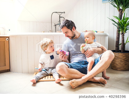 Father with two toddlers brushing teeth in the bathroom at home. 40298396