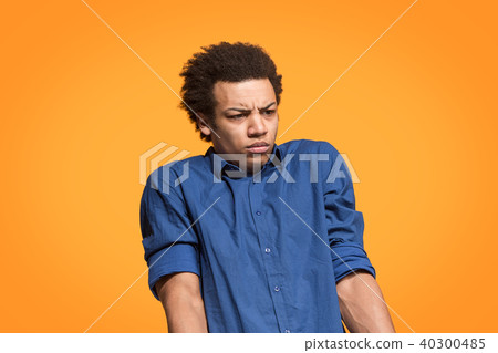 Let me think. Doubtful pensive man with thoughtful expression making choice against orange Let me think. Doubtful pensive man with thoughtful expression making choice against orange 40300485