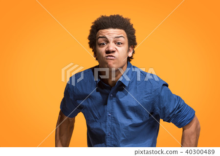 The young emotional angry man screaming on orange studio background The young emotional angry man screaming on orange studio background 40300489