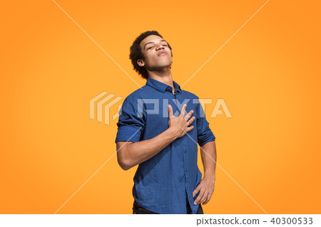 Beautiful male half-length portrait isolated on orange studio backgroud. The young emotional 40300533