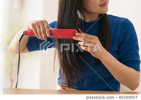 Young Woman With Long Hair Using Hair Iron 40309057