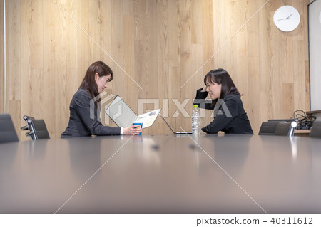 Two women in suits in a meeting room Two women in suits in a meeting room 40311612