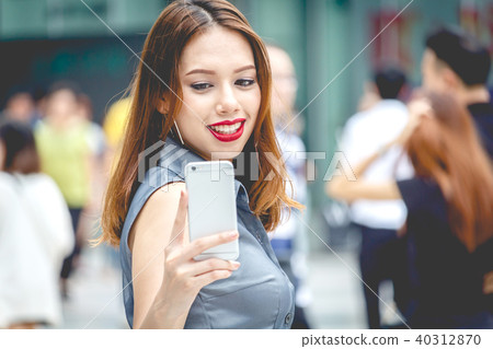 Portrait of young woman using smartphone on street 40312870