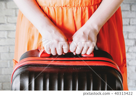 Woman holding suitcase on wall background Woman holding suitcase on wall background 40313422