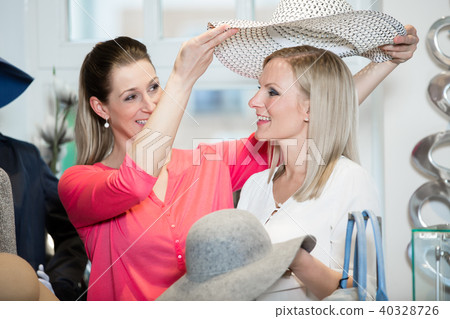 Girlfriends on shopping spree trying ladies hats and other fashion 40328726