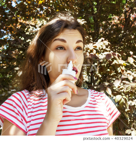 A woman is dripping nasal drops in a blocked nose A woman is dripping nasal drops in a blocked nose 40329024
