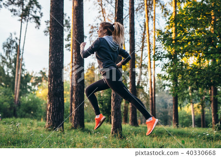 Pretty female gymnast practicing outdoors doing back bend jump Pretty female gymnast practicing outdoors doing back bend jump 40330668