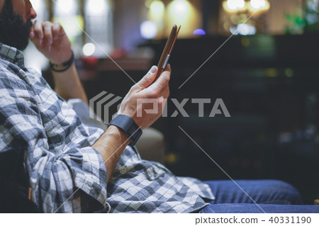 Handsome bearded man using electronic reader book computer while resting in lobby hotel. Man using 40331190
