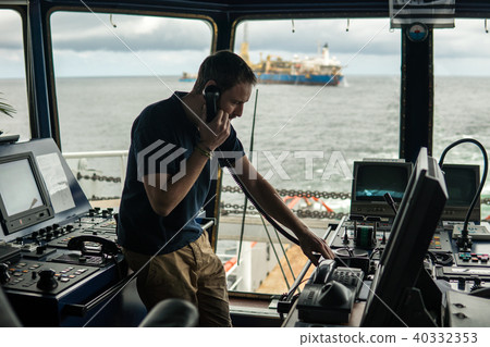 Deck navigation officer on the navigation bridge. He looks through binoculars 40332353