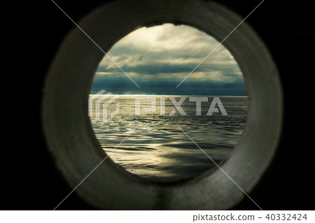 Ship window or porthole view with a relaxing seascape and dark grey clouds 40332424