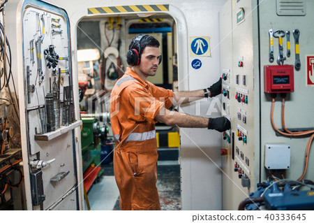 Marine engineer officer controlling vessel engines in engine control room ECR 40333645