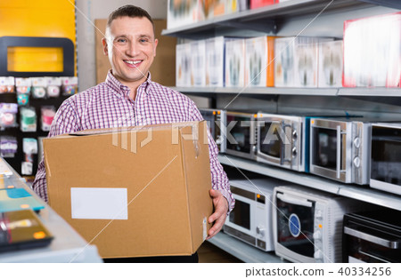 Man with packed purchases in household appliances section in shop Man with packed purchases in household appliances section in shop 40334256