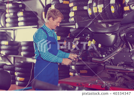 man in coveralls checking motorcycle 40334347