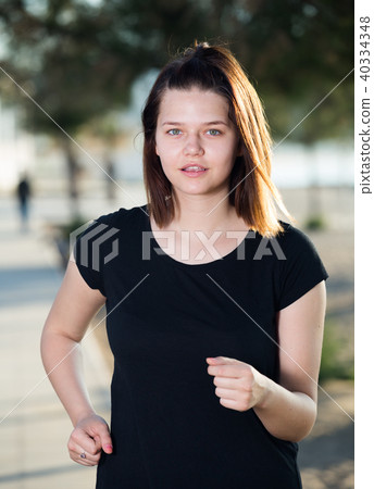 Adult female in black T-shirt is jogging 40334348