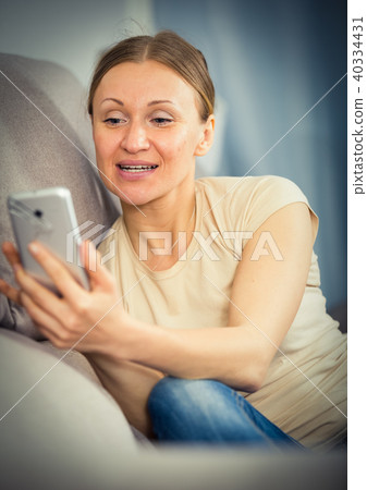 Woman with phone on sofa 40334431