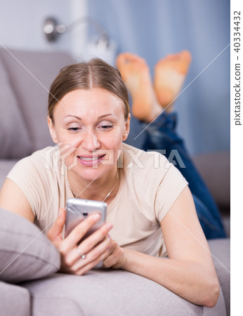 Woman lying on sofa with phone Woman lying on sofa with phone 40334432