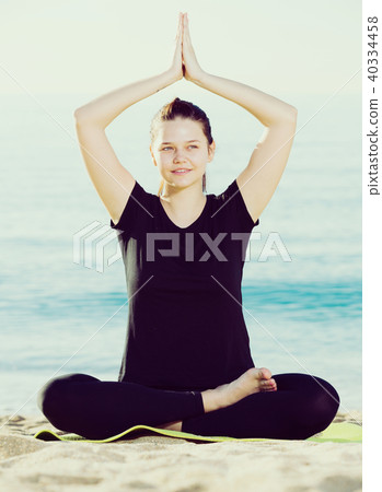 Athletic woman in black T-shirt is sitting and practicing pranayama 40334458