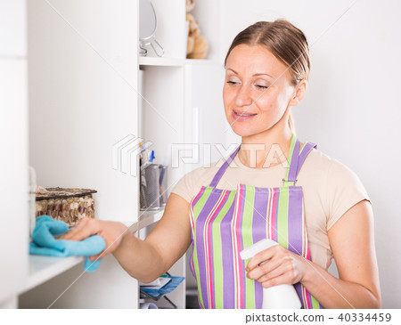 Positive woman wiping shelves 40334459