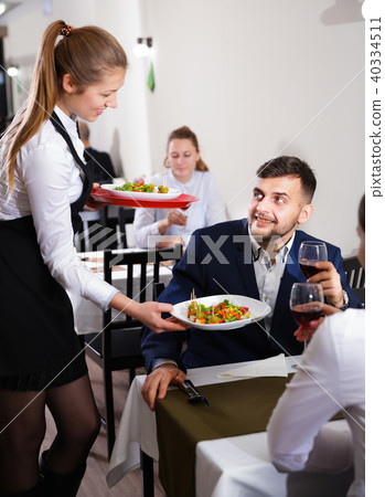 Welcoming female waiter is serves the dish to client in restaurante 40334511