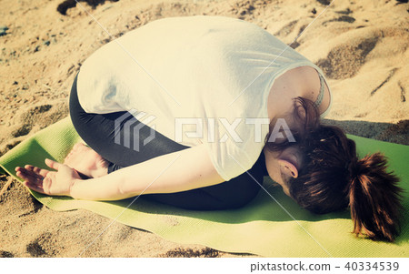 Smiling adult female in white T-shirt is practicing stretching 40334539