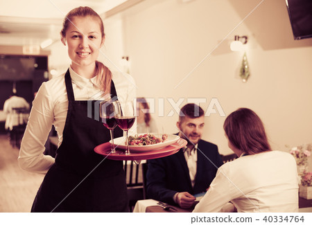 Affable female waiter is standing with order in luxury restaurante 40334764