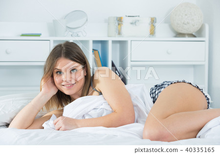 Portrait of young smiling girl lounging in bed 40335165