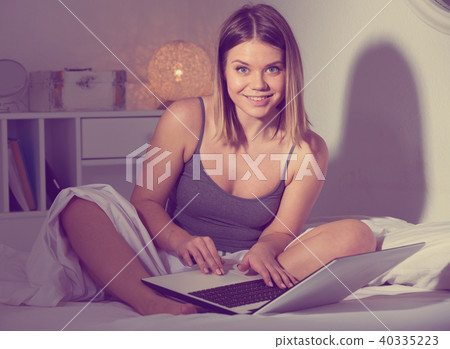 Portrait of sexy positive woman sitting with laptop in bed 40335223
