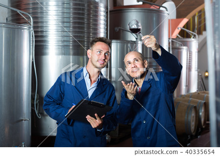 Two employees with wine sample at winery. 40335654