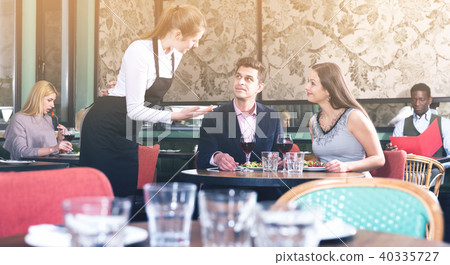 Waitress talking with satisfied couple in restaurant Waitress talking with satisfied couple in restaurant 40335727