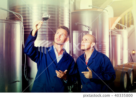 Happy two workers examining sample of wine 40335800